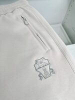 Pantaloni jogger beige con tasca zip e logo ricamato, perfetti per comfort e stile casual.