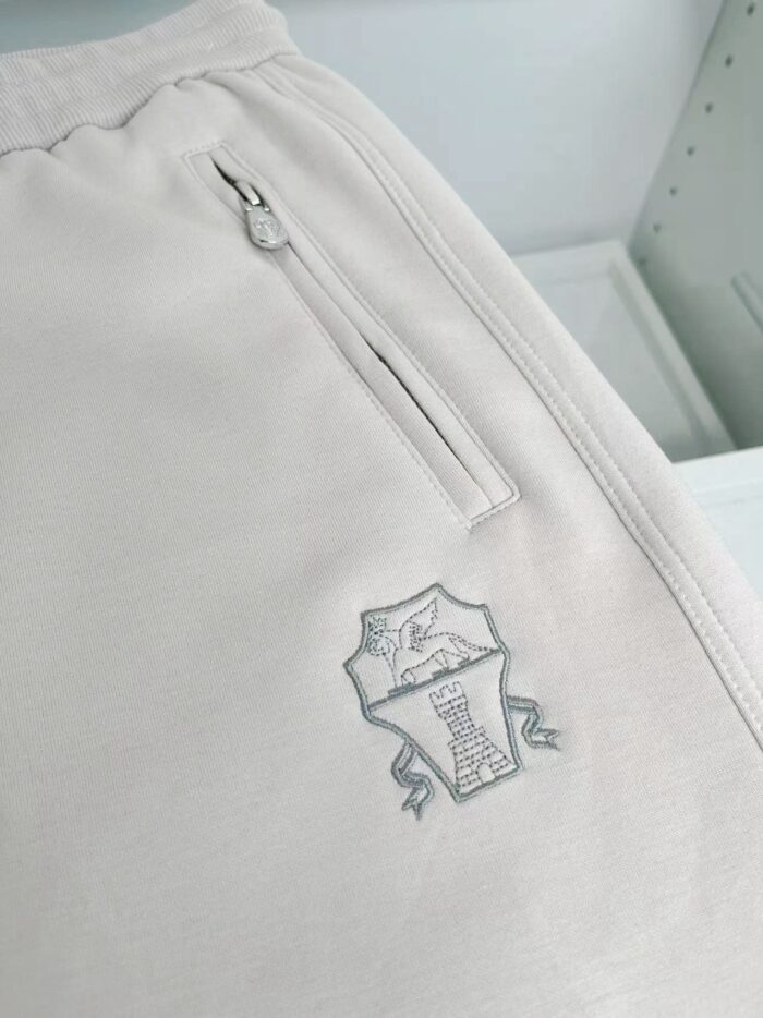 Pantaloni jogger beige con tasca zip e logo ricamato, perfetti per comfort e stile casual.