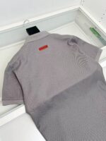 Maglietta polo grigia con dettaglio rosso, stile minimalista e design moderno.