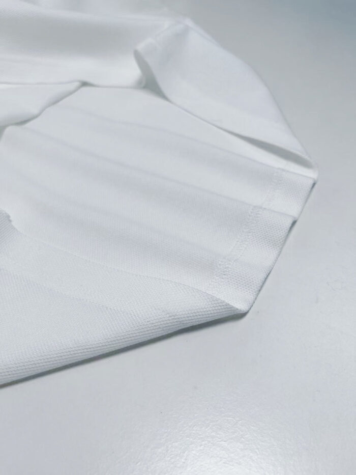 Tessuto bianco morbido su superficie riflettente, elegante e versatile per moda e decorazione.