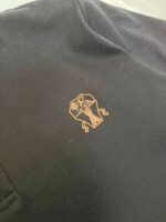 Giacca sportiva con logo stilizzato arancione e dettagli eleganti su tessuto scuro.