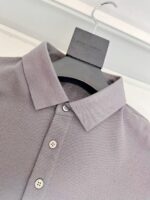 Maglietta polo moderna in lavanda con dettagli eleganti e stile versatile, su appendiabiti nero.