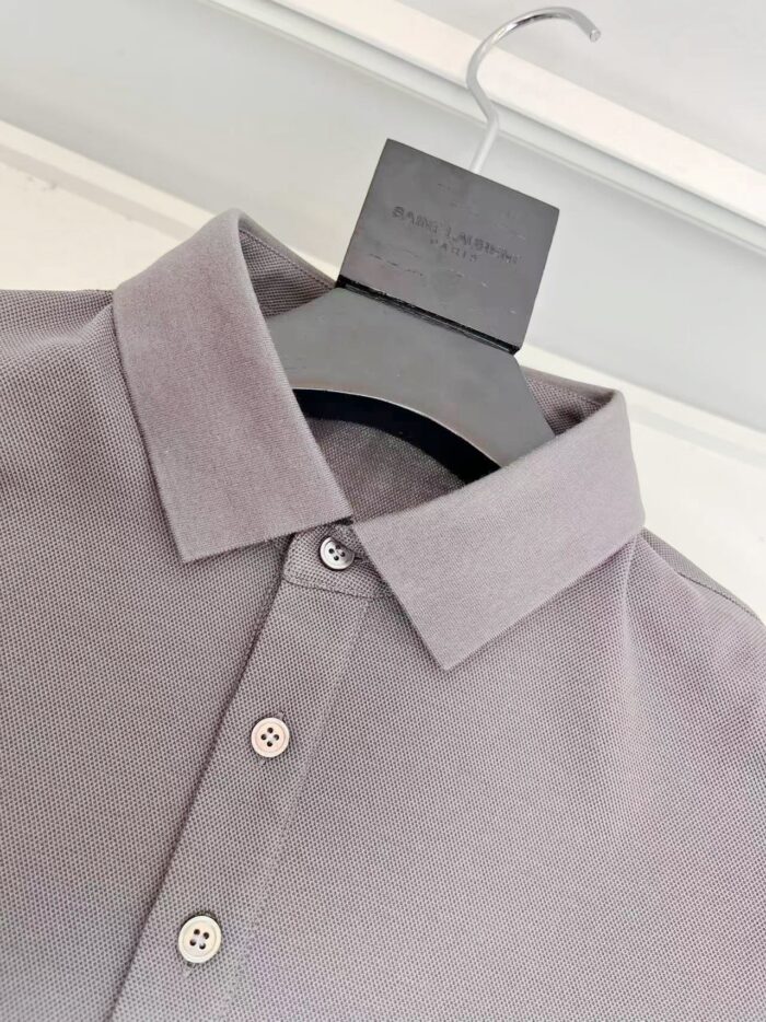 Maglietta polo moderna in lavanda con dettagli eleganti e stile versatile, su appendiabiti nero.