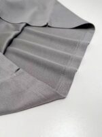 Tessuto grigio elegante con plissettature e dettagli raffinati, ideale per arredamento e moda.