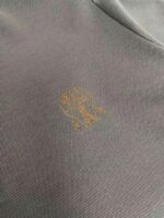 Tessuto grigio con logo dorato, ideale per abbigliamento sportivo e casual di alta qualità.