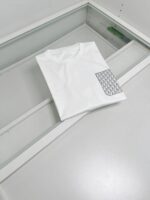 Maglietta bianca semplice con tasca geometrica moderna, stile minimalista e design contemporaneo.