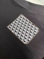 Maglietta nera con patch geometrico in bianco e grigio, stile moderno ed elegante.