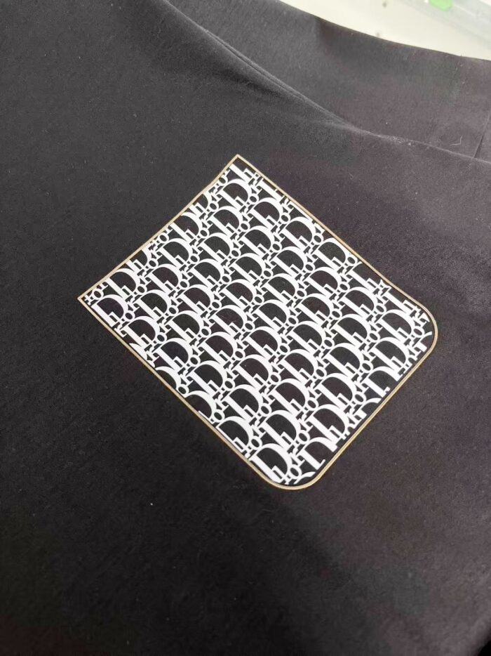 Maglietta nera con patch geometrico in bianco e grigio, stile moderno ed elegante.