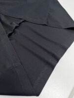 Tessuto nero sintetico, elegante, con pieghe morbide e finitura lucida, ideale per abbigliamento e arredi.