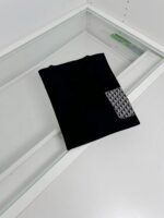 Maglietta nera elegante con patch geometrico, perfetta per uno stile minimalista e moderno.