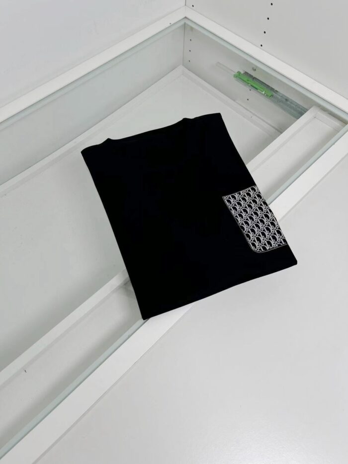 Maglietta nera elegante con patch geometrico, perfetta per uno stile minimalista e moderno.