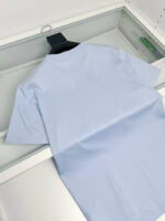 Camicia blu leggera piegata ordinatamente su uno scaffale contemporaneo per unvestiario organizato.