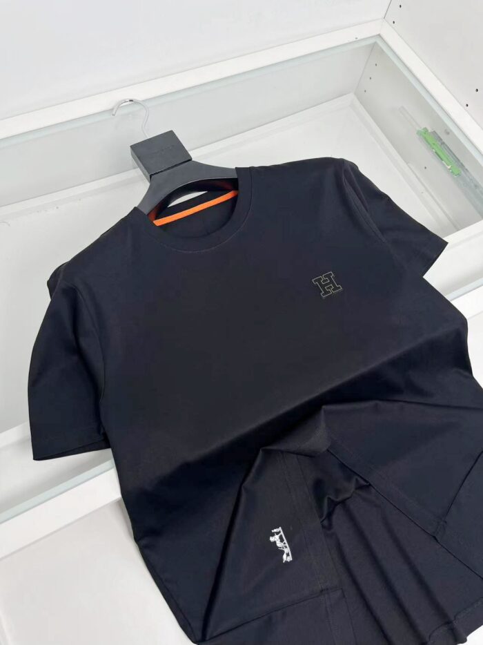 Maglietta nera minimalista con logo riflettente, su appendiabiti elegante, stile casual e sofisticato.