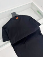 T-shirt nera minimale con dettaglio arancione sul retro, morbida e versatile, ideale per ogni stile.