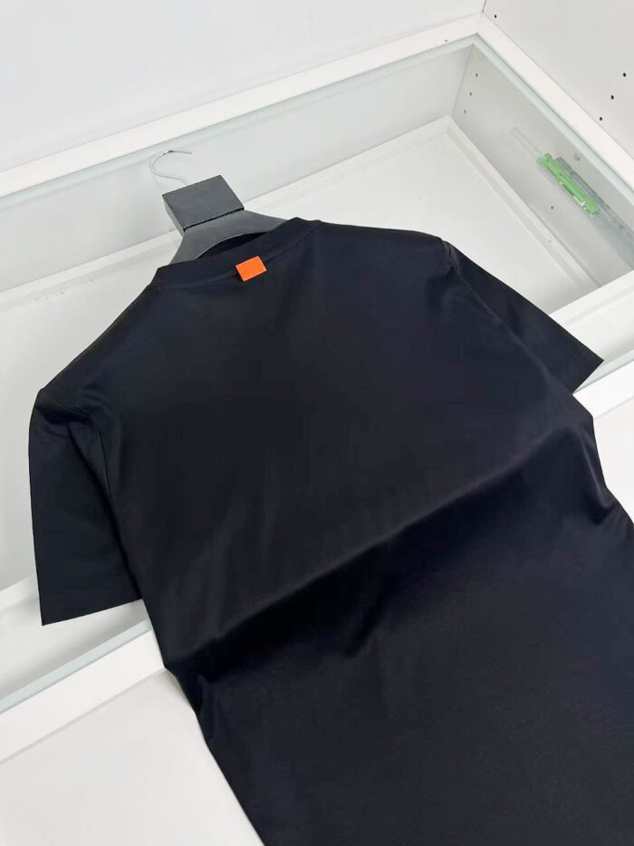 T-shirt nera minimale con dettaglio arancione sul retro, morbida e versatile, ideale per ogni stile.
