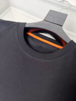 Maglietta nera con interno arancione, design moderno e dettagli di alta qualità.