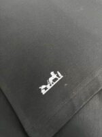 Logo equestre minimalista su tessuto nero raffinato, simbolo di eleganza e qualità.
