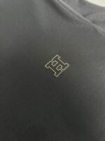 Tessuto nero con logo dorato elegante, ideale per abbigliamento di alta qualità e stile semplice.