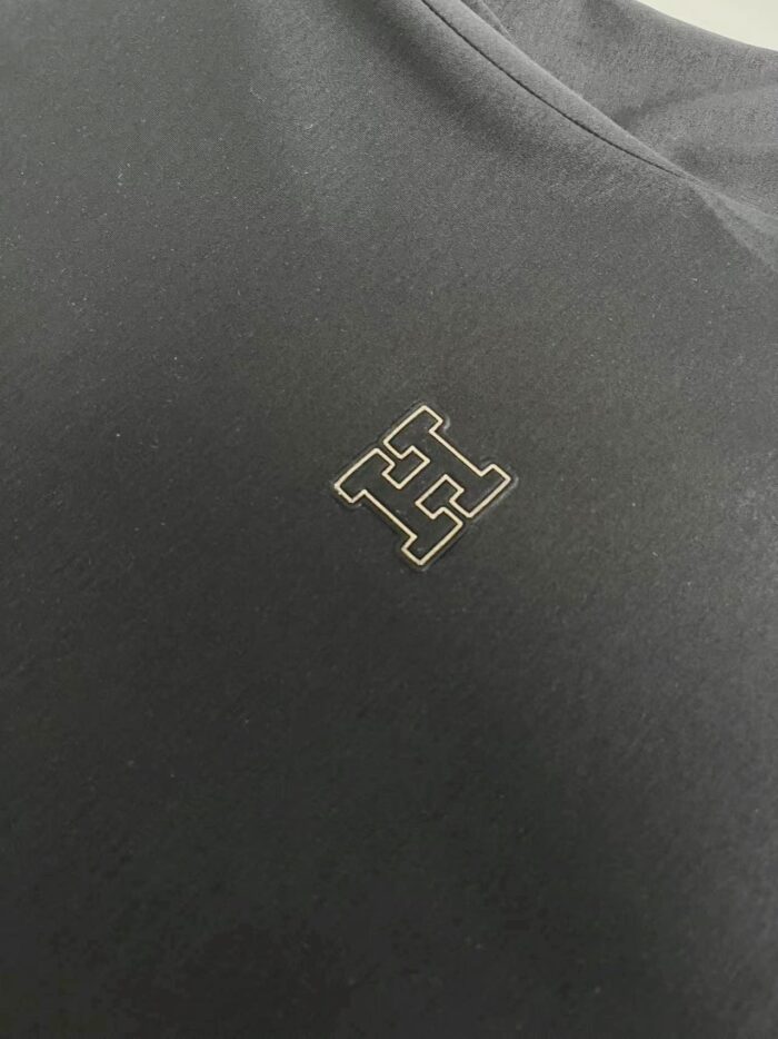Tessuto nero con logo dorato elegante, ideale per abbigliamento di alta qualità e stile semplice.