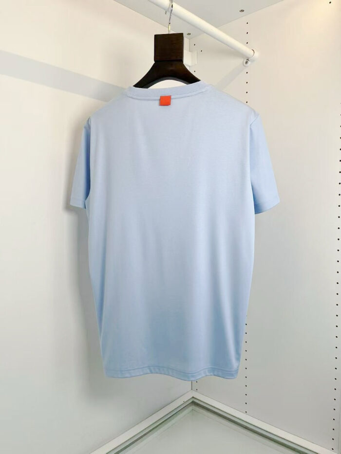 Maglietta casual blu chiaro con etichetta arancione, stile moderno, comoda e leggero tessuto.