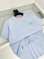 T-shirt celeste con dettaglio arancione e logo sottile, stile casual e moderno, ideale per l’estate.