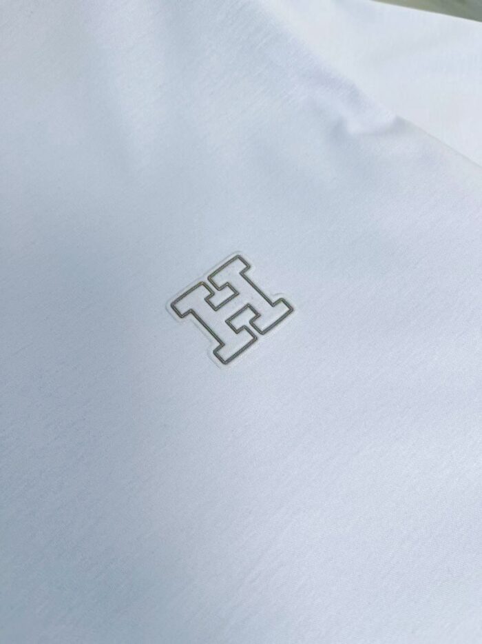 Maglietta bianca con logo grigio minimalista, tessuto elegante e stile raffinato.