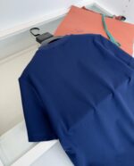 Maglietta navy, borsa elegante con fiocco blu, stile minimalista e moderno in ambientazione luminosa.