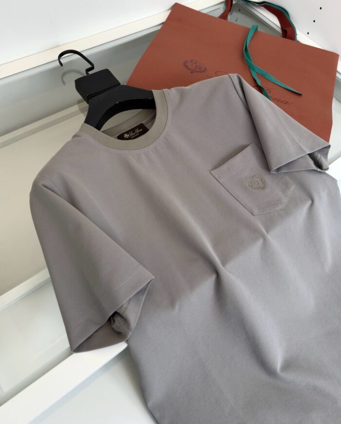 T-shirt grigia casual con borsa in pelle elegante e dettagli minimalisti.