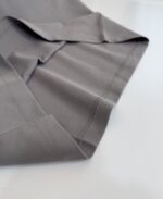 Tessuto grigio sottile e lucido con cuciture precise, ideale per abbigliamento elegante e versatile.