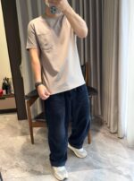 Persona in stile casual con t-shirt beige, pantaloni navy e sneakers bianche in casa elegante