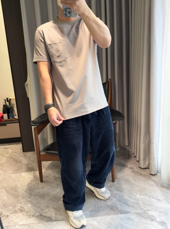 Persona in stile casual con t-shirt beige, pantaloni navy e sneakers bianche in casa elegante