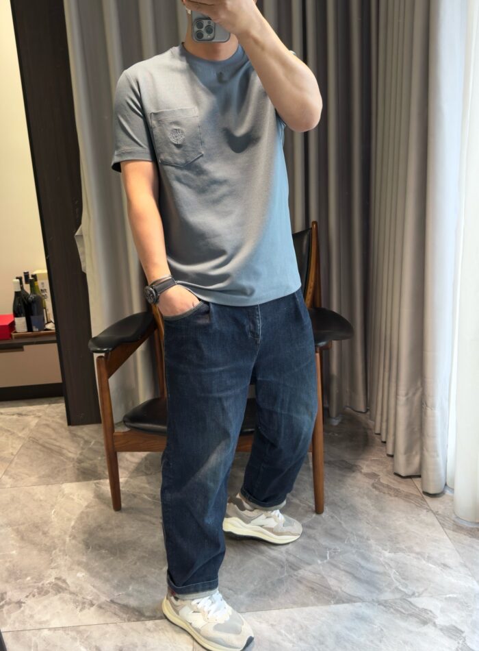 Persona che scatta selfie in look casual con jeans e sneakers in ambiente moderno e accogliente.
