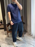 Persona in jeans e sneakers bianche in ambiente moderno e luminoso con tende e pavimento lucido.