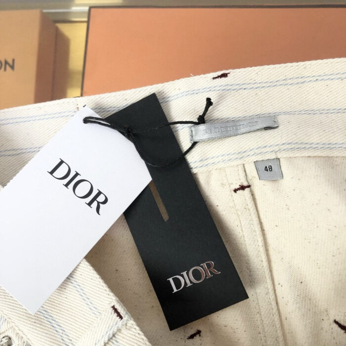 Etichetta Dior su abbigliamento beige di lusso, dettagli eleganti e qualità artigianale.