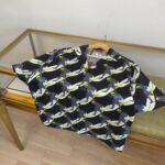 Camicia corta estiva con design astratto, colori vivaci su sfondo blu navy, stile casual e moderno.