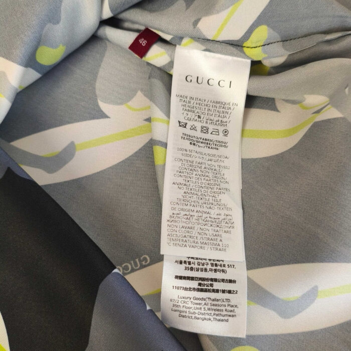 Tessuto Gucci con design astratto, etichetta di lusso e istruzioni di cura multilingue.