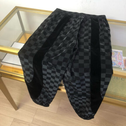 Pantaloni relaxed con motivo checkerboard e pannelli neri in velluto moda streetwear moderna.