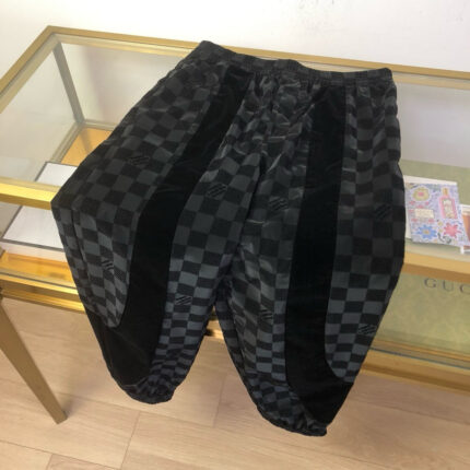 Pantaloni oversized con motivo checkerboard in velluto e dettagli in tessuto nero texturizzato.