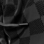 Tessuto nero tecnicizzato con pattern a diamante e cordino regolabile per abbigliamento outdoor.