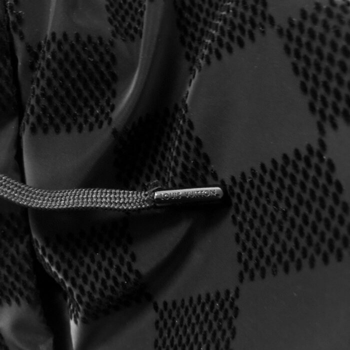 Tessuto nero tecnicizzato con pattern a diamante e cordino regolabile per abbigliamento outdoor.
