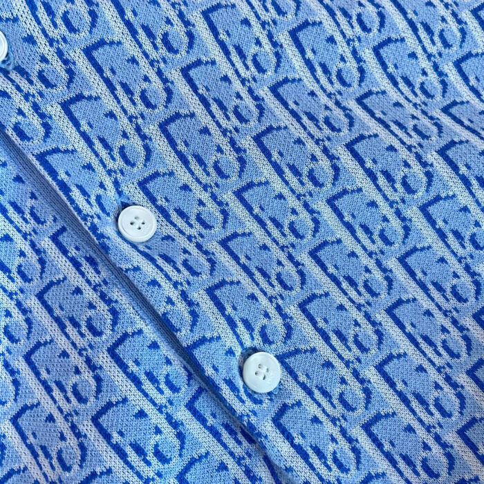 Camicia blu con motivo geometrico e bottoni bianchi, tessuto elegante e dettagli raffinati.