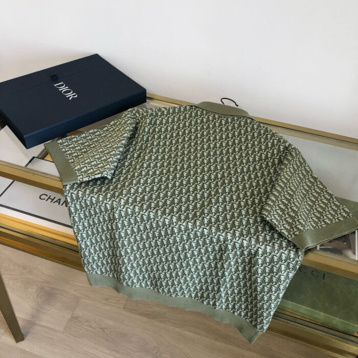 Camicia moderna verde oliva su tavolo di design con scatola elegante e riflessi luminosi.