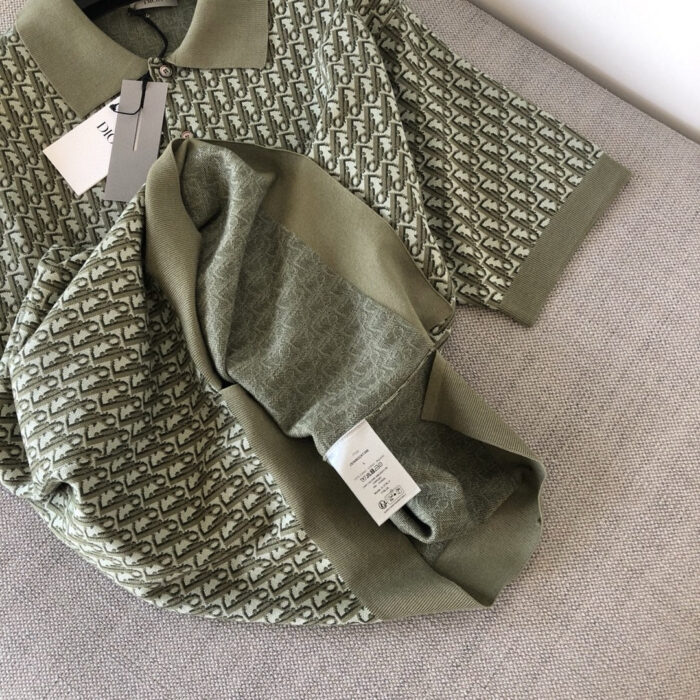 Maglietta polo verde moderna con dettagli eleganti e tessuto a motivi su sofa chiaro.
