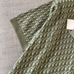 T-shirt verde oliva con dettagli eleganti, pattern raffinato e polsini a costine di stile moderno.