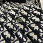 Tessuto a pattern con bottoni verde muto, stile moderno e classico, dettagli di alta qualità.
