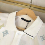Maglietta polo bianca con motivi colorati, dettagli eleganti e stile casual chic.