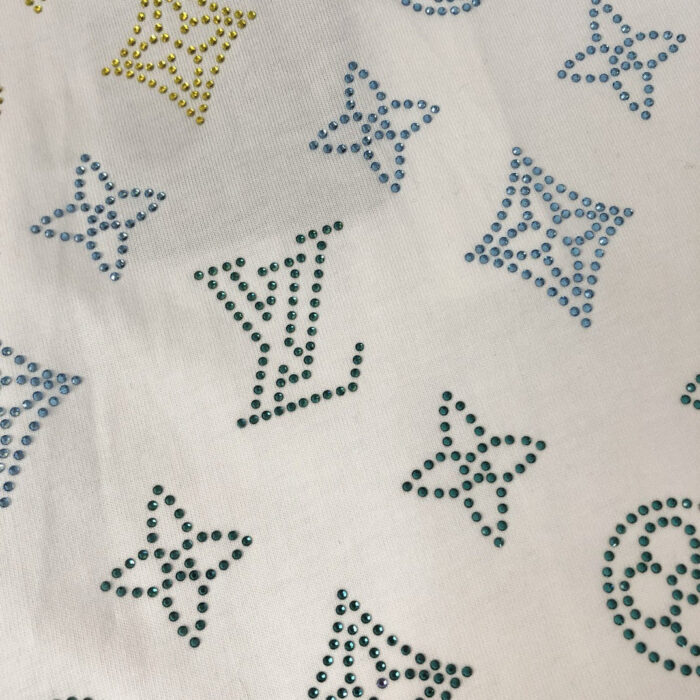 Tessuto di lusso con rhinestones, motivi star e logo LV, elegante e scintillante.