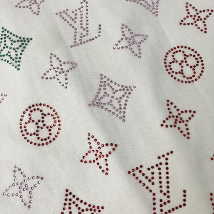 Tessuto di lusso con loghi colorati e rhinestones scintillanti, perfetto per moda elegante e glamour.