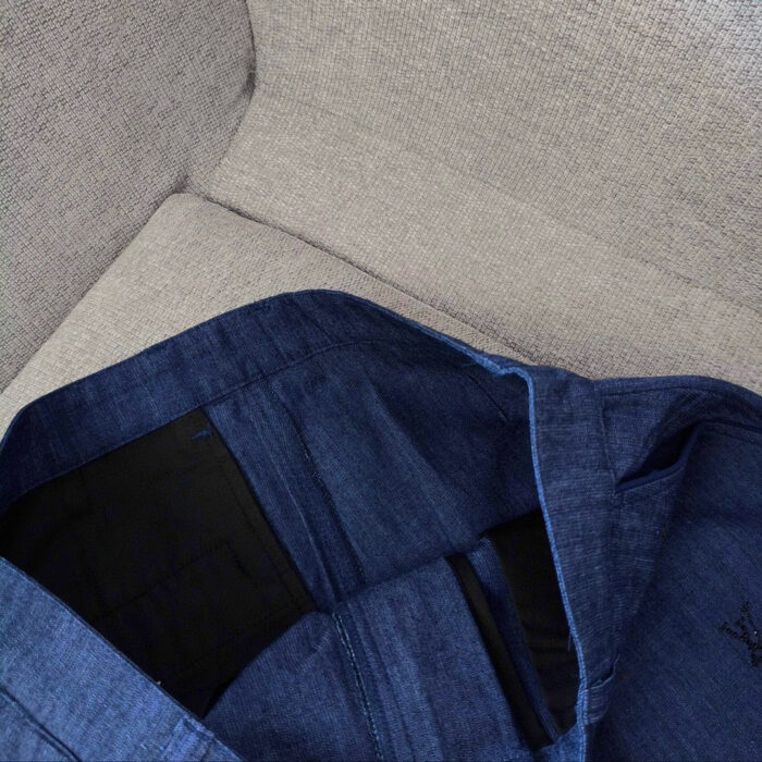 Giacca blu scuro con tasche interne, dettagli moderni e stile pratico, su superficie neutra.