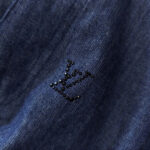 Dettaglio denim blu con logo ricamato nero, stile elegante e casual.